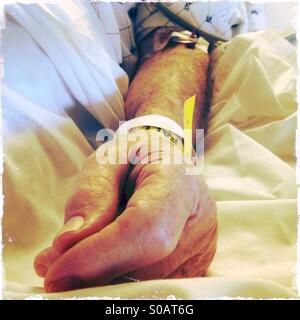 Une personne âgée, homme bras du patient avec une iv. Un bracelet jaune avec le mot tomber sur c'est sur son poignet. Banque D'Images