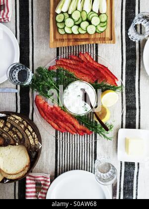 Déjeuner scandinave de deux tons accueil guéri avec le concombre gravlax sauce yogourt, du pain et du beurre et de tranches de concombre et fenouil. Banque D'Images