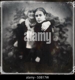 Grand-mère et petite-fille portrait noir et blanc à l'extérieur en face de la floraison hydrangea bush. Banque D'Images