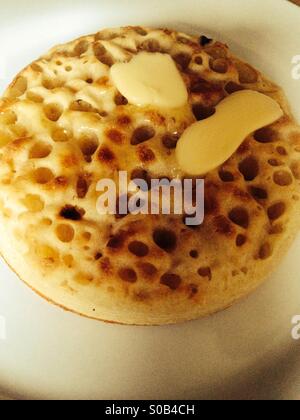 Crumpet Hot buttered on a white plate Banque D'Images