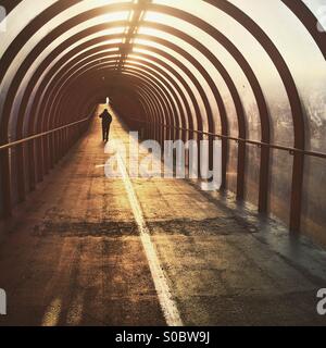 Une silhouette d'un homme marchant dans un tunnel au lever du soleil à Glasgow