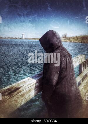 Une dame avec un noir veste en regardant les vagues sur un lac (1). Banque D'Images