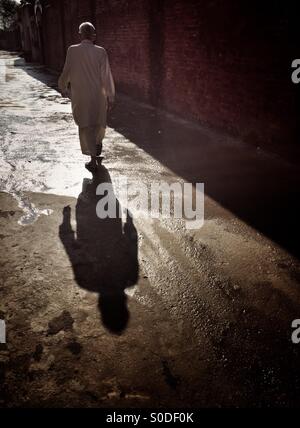 Homme marchant dans l'allée Kharian village Pakistan Banque D'Images