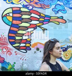 Jeune femme brune en face de l'écriture graffiti wall Banque D'Images