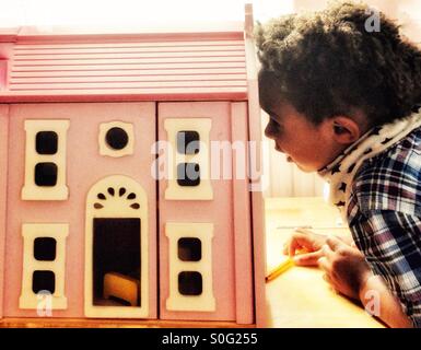 Un petit Garçon jouant avec une maison de poupées. Banque D'Images