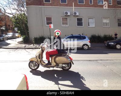 Personne conduisant un scooter avec un cercle rouge Target (détail) blanc sur son casque Banque D'Images