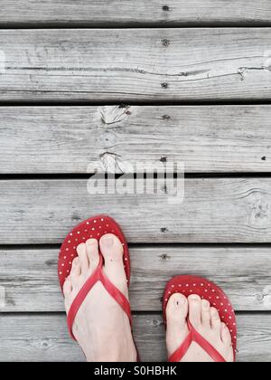 Tongs rouge sur un quai en bois, chalet d'été en Finlande Banque D'Images