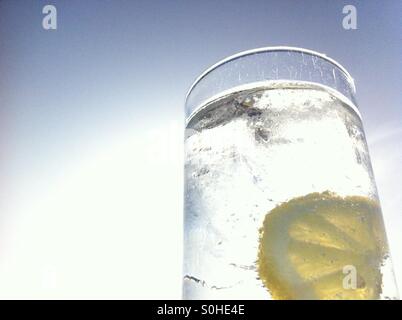 Close up of gin tonic avec du citron et la glace contre ciel bleu Banque D'Images