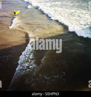 Un surfeur en aller à aller faire du surf. Manhattan Beach, Californie, États-Unis. Banque D'Images