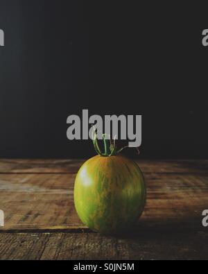 Tomate green zebra organiques sur une boîte en bois avec fond noir Banque D'Images