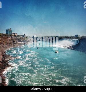 Vue du côté canadien des chutes du Niagara à côté américain de Niagara Falls avec des bateaux sur la rivière ci-dessous Banque D'Images