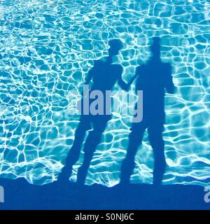 Ombre d'un couple en vacances debout à côté d'une piscine. Banque D'Images