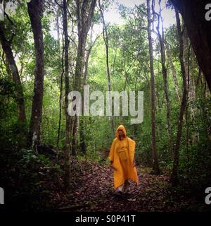 Une femme portant un poncho jaune promenades dans la jungle dans la ville maya de Mirador, Peten, Guatemala Banque D'Images