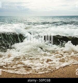 Marée montante avec vague se précipiter sur les rochers Banque D'Images