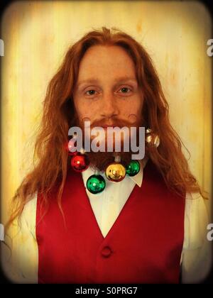 Jeune homme aux cheveux rouges avec noël dans sa barbe. Banque D'Images