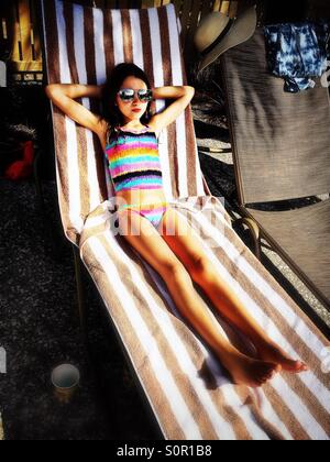 Girl relaxing on lounge chair in sun Banque D'Images