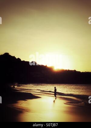 Silhouette sur lone man on beach at sunset Banque D'Images
