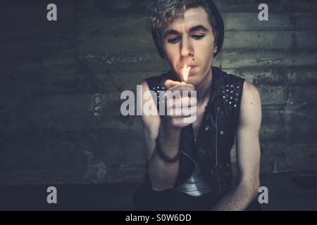 Jeune gamin en cuir gilet allumer une cigarette. Banque D'Images