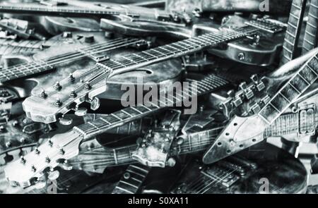 Guitares jetés dans une pile malpropre. Image en noir et blanc avec une finition métallique. Beaucoup de guitares. Banque D'Images