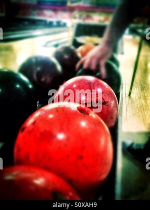 Une personne choisit une boule de bowling à partir de la balle revenir à un bowling. Banque D'Images