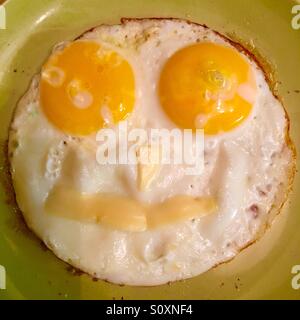 Oeufs frits Smiley sur une plaque verte Banque D'Images