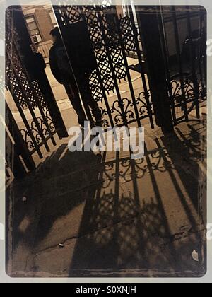 Homme marchant à travers portes en fer forgé à Sniffen Court, Murray Hill, New York. Banque D'Images