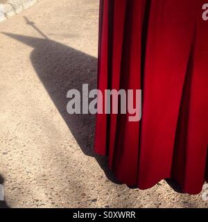 L'ombre d'un pénitent portant une cape rouge à Pâques Semaine Sainte à Astorga, Maragateria, Leon, Espagne Banque D'Images