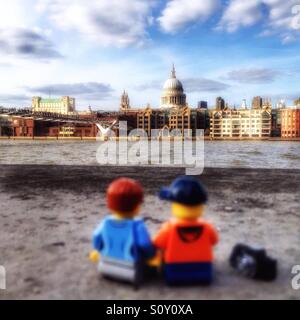 Un couple Lego assis à la Tamise à Londres à l'horizon avec St Paul et le Millennium Bridge Banque D'Images