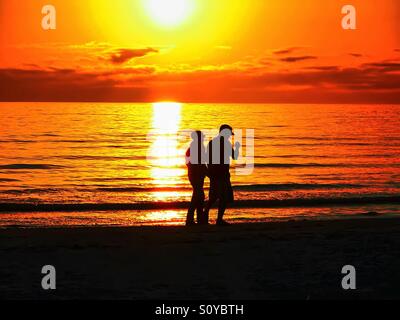 Couple en train de marcher sur la plage pendant le coucher du soleil en Floride Banque D'Images