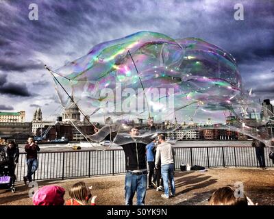 Musicien ambulant divertit les foules sur la rive sud de Londres en soufflant d'énormes bulles de savon. La Cathédrale St Paul peut être vu dans l'arrière-plan Banque D'Images