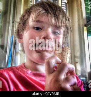 Cinq ans garçon mangeant du chocolat ice cream cone Banque D'Images