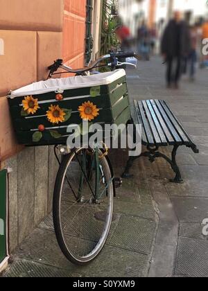 Un vélo avec un panier vert décorée de tournesols, appuyé contre un mur à Levanto, Italie. Banque D'Images