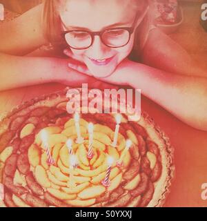 Petite fille avec des lunettes à son anniversaire à tarte aux 8 BOUGIES Banque D'Images