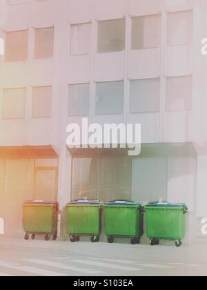 4 poubelles en face d'un immeuble de bureaux Banque D'Images