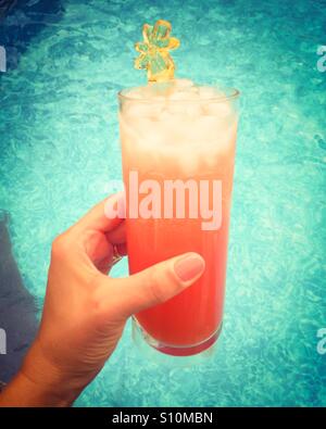 Closeup of a woman's hand holding une boisson glacée sur une chaude journée à côté d'une piscine. Banque D'Images
