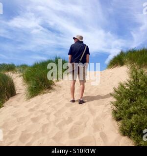 Man walking up sand dunes Banque D'Images