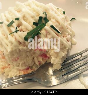 À Malaga en Espagne Salade de crabe et légumes avec la souris dans la mayonnaise avec la fourchette sur l'assiette blanche et décoration persil Banque D'Images