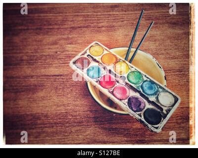 Palette de peinture pour enfants avec une cuvette d'émail et deux brosses sur une table en bois Banque D'Images