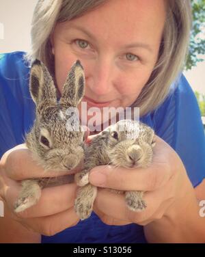 Une femme tient deux bébés lapins. Banque D'Images