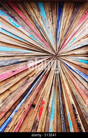 Un abstrait art fond fabriqués à partir de bandes colorées de vieux bois de dérive qui convergent sur un point central. Banque D'Images