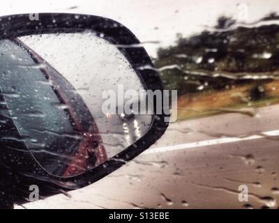 Side-View mirror un jour de pluie sur une autoroute allemande avec une voiture Banque D'Images