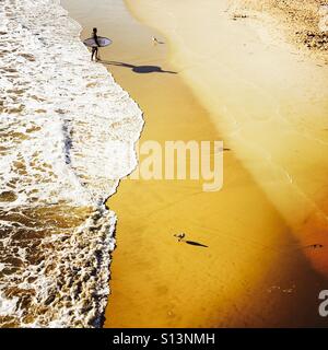 Un homme marche Surfer sur la plage après le surf. Manhattan Beach, Californie, États-Unis. Banque D'Images