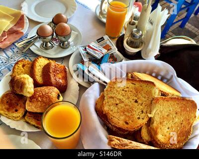 Un hôtel petit-déjeuner avec des œufs, du pain, des viennoiseries et du jus d'orange. Banque D'Images