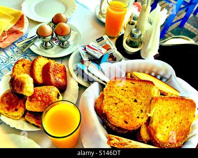 Un hôtel petit-déjeuner avec des œufs, du pain, des viennoiseries et du jus d'orange. Banque D'Images