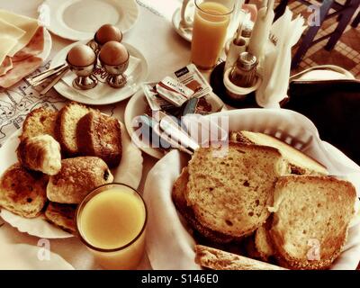 Un hôtel petit-déjeuner avec des œufs, du pain, des viennoiseries et du jus d'orange. Banque D'Images