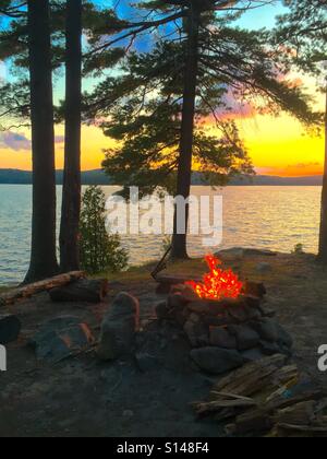 Les flammes de feu de camp au lac avec la lumière du soleil plus de Forest Hills Banque D'Images