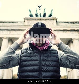 Homme portant un casque de réalité virtuelle VR à Brandenburg gate in Berlin Banque D'Images