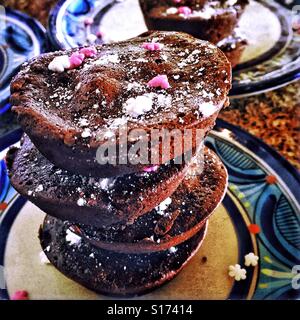 Double chocolat Fudgy brownies ronde sont empilés sur une assiette et saupoudré de sucre en poudre et les bonbons en forme de fleur. Banque D'Images