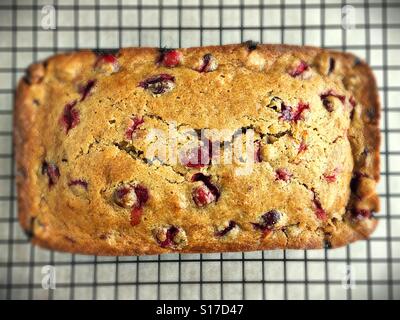 Une miche de pain aux canneberges et à l'orange sur une grille de refroidissement. Banque D'Images