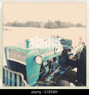 Un vintage Ford tracteur dans un champ neigeux en Nouvelle Angleterre. Banque D'Images